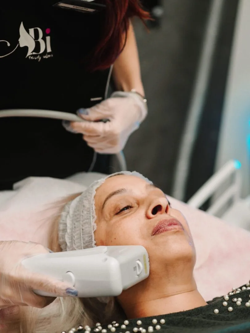 Терапевт на Abi Beauty прилага HIFU накрайник по бузата на клиентка над 50 години